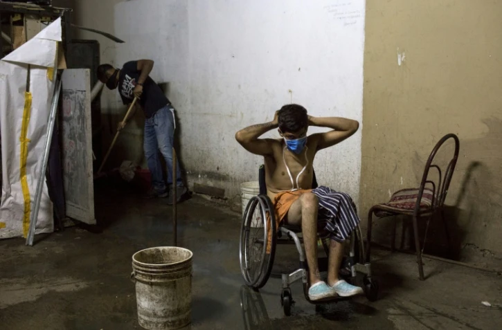 Johan Medina, 31 ans, met un masque après avoir pris un bain dans le sous-sol d'un ministère où il loge dans des conditions déplorables à Caracas, le 9 octobre 2020