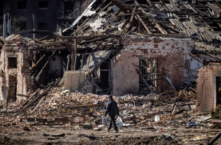 Un homme marche près d'un immeuble détruit dans la ville de Trostyanets, dans le nord-est de l'Ukraine, le 29 mars 2022