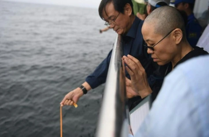Liu Xia, veuve du Prix Nobel de la Paix Liu Xiaobo, prie alors que les cendres de son époux sont dispersées en mer, le 15 juillet 2017 au large de la ville de Dalian en Chine. Photographie fournie par le service de presse de Shenyang.
