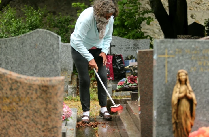 Une femme nettoie une tombe le 28 avril 2020 dans un cimetière de Reims qui vient de rouvrir