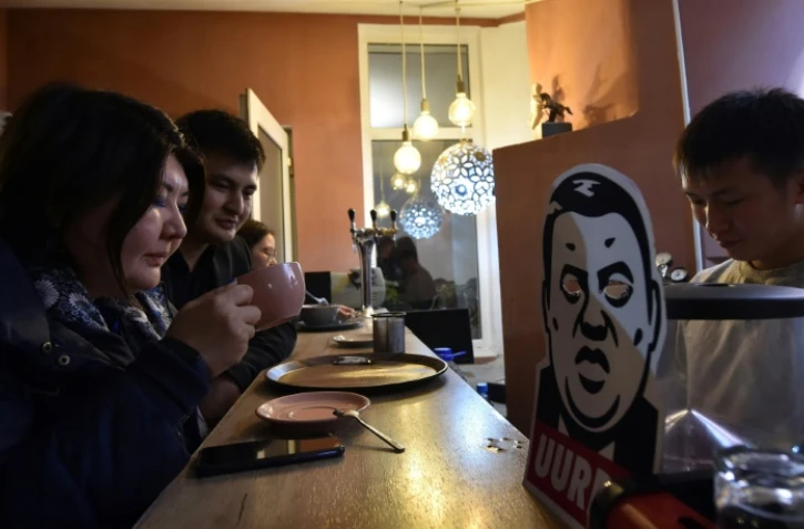 Des consommateurs boivent une boisson au café Kommouna à Bichkek, le 5 décembre 20190 devant un dessin représentant Rayimbek Matraimov, un symbole de la corruption au Kirghiztan