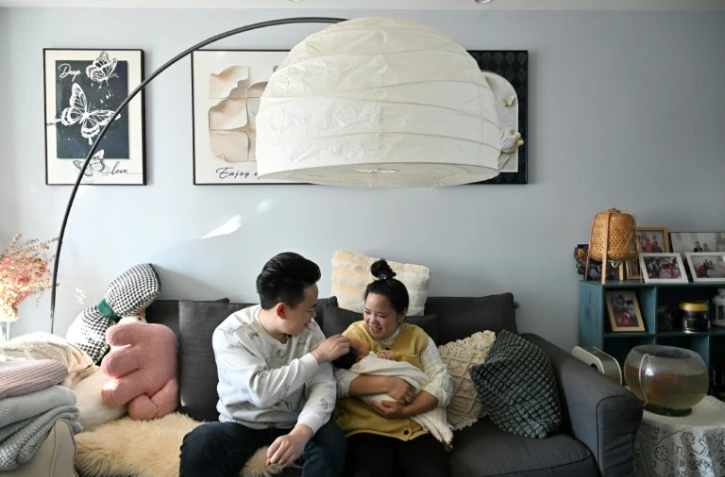 Zhang Xiaofei, 32 ans, et son époux Zhu Yunfei, 36 ans, avec leur fille de trois semaines dans leur appartement de Langfang, en périphérie de Pékin, le 6 mars 2026