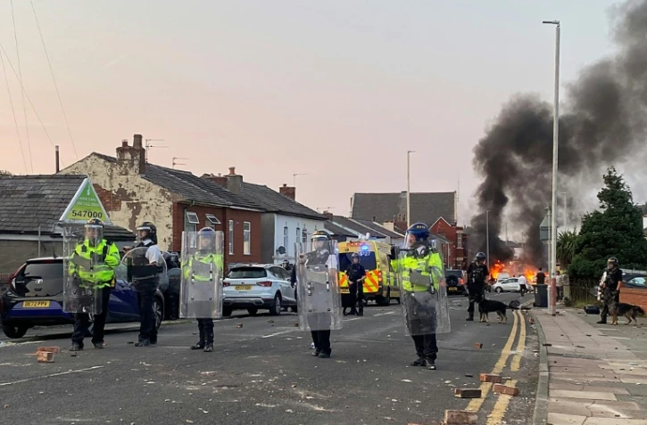 Un feu allumé par des manifestants près de la mosquée de Southport en Angleterre, gardée par des policiers, le le 30 juillet 2024 au lendemain d'une attaque meurtrière contre des enfants