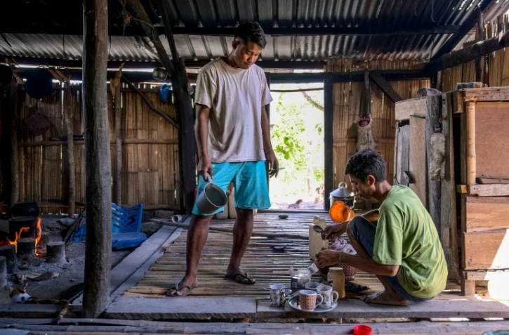 Le noble Umbu Ana Rara (g) regarde son esclave (d) Kanisius Kanyali Hambarita préparer des boissons au village de Tanggedu, dans l'est de l'île de Sumba, le 23 juin 2026 en Indonésie