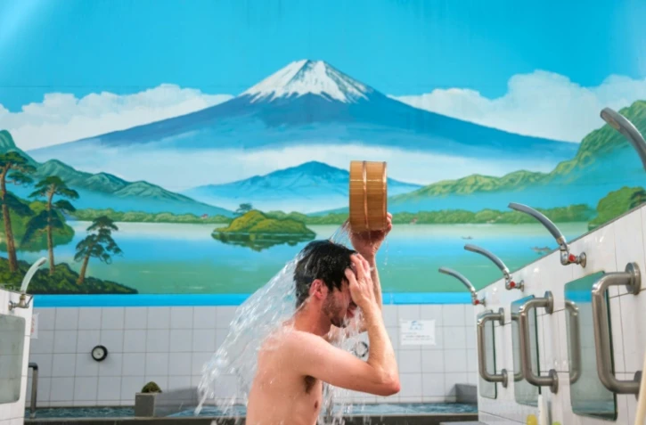 Sam Holden, co-directeur d'une association de sauvegarde de bains publics, se baigne au sento Inari-yu, le 6 juillet 2022 à Tokyo 