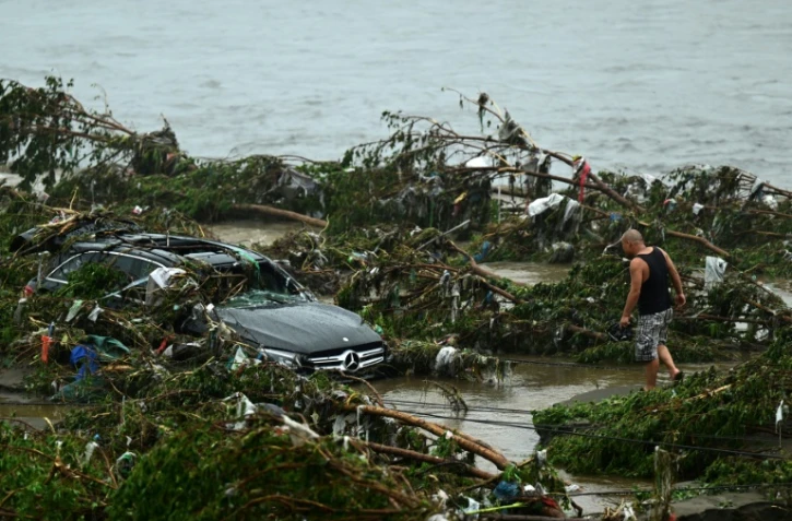 Un homme regarde une voiture endommagée suite à de fortes pluies dans le district de Fangshan à Pékin, le 1er août 2023