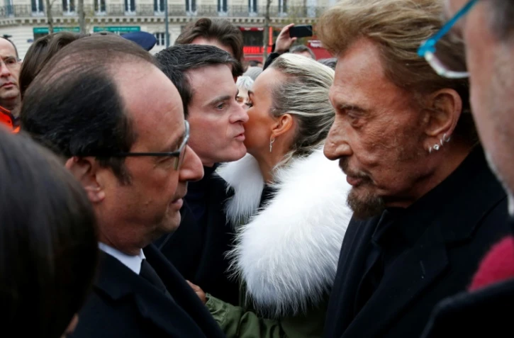 Le président Francois Hollande parle avec Johnny Hallyday tandis que sa femme Laetitia embrasse le Premier ministre Manuel Valls à la fin d'une cérémonie le 10 jancier 2016, un an après l'attentat contre Charlie Hebdo