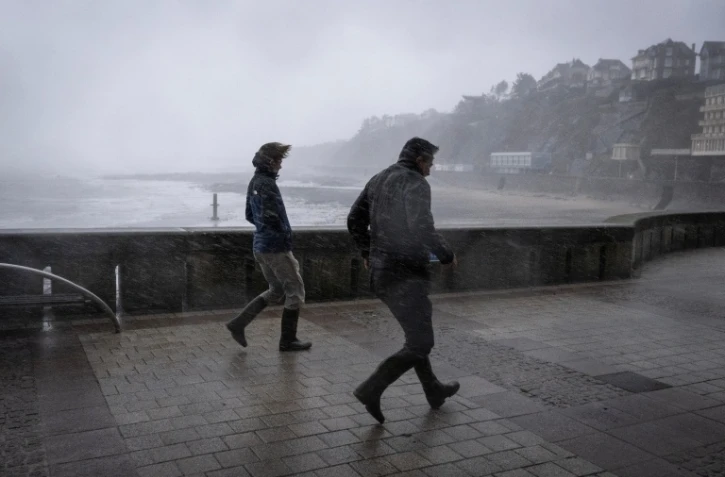 Des promeneurs pris dans les bourrasques de la tempête Austen sur le front de mer à Granville, dans la Manche, le 23 octobre 2026