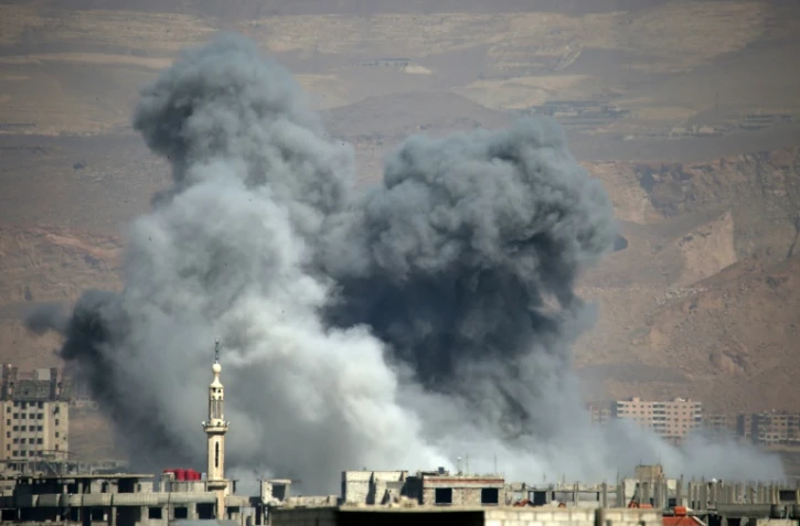 De la fumée s'élève après un bombardement du régime au-dessus de la ville sous contrôle rebelle d'Arbine, dans la Ghouta orientale, près de Damas, le 11 mars 2018