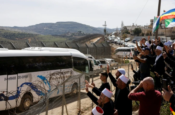 Des druzes saluent l'arrivée d'un groupe de religieux venus de Syrie, le 14 mars 2025 dans le village de Majdal Shams, sur le plateau syrien du Golan annexé par Israël
