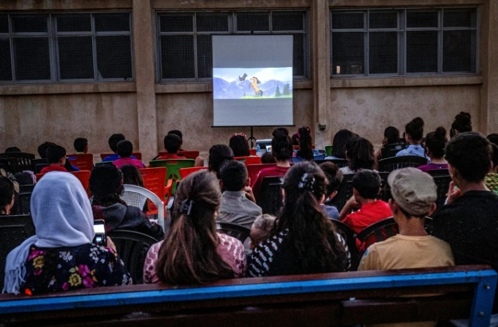 Des enfants assistent à une projection d'un film de Charlie Chaplin dans une école du village de Sanjak Saadoun en Syrie, le 28 juillet 2019