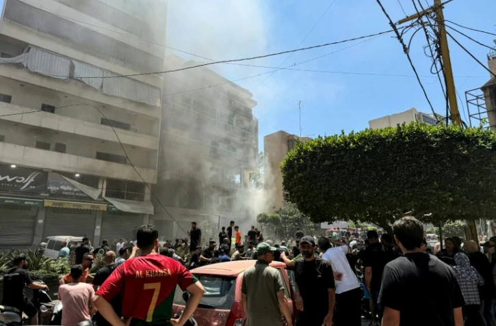 Des habitants sur le site d'une frappe aérienne israélienne qui a ciblé un bâtiment dans la banlieue sud de Beyrouth, le 14 juin 2026 au Liban