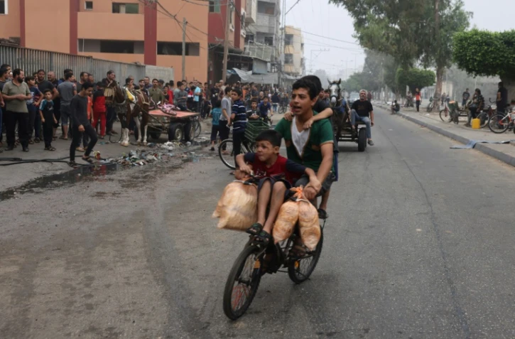 Des jeunes portent des sacs de pain sur du vélo à Rafah, dans le sud de la bande de Gaza, le 28 octobre 2023