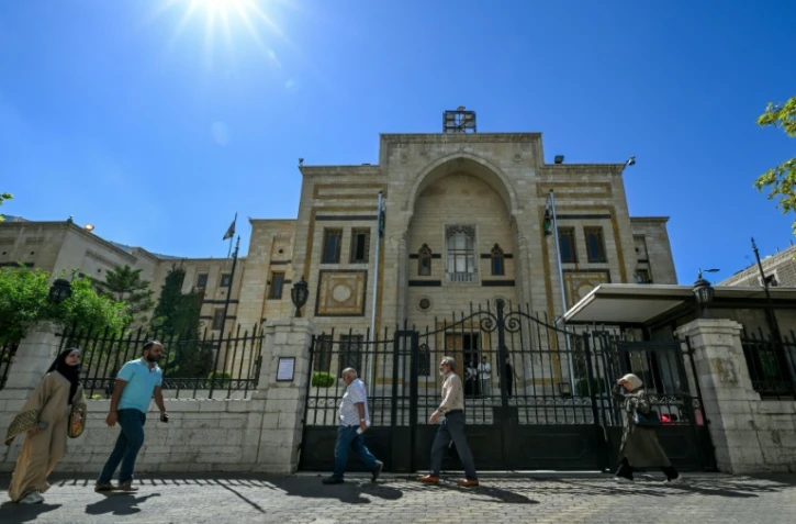 Des personnes passent devant le bâtiment du Parlement à Damas, le 1er octobre 2025