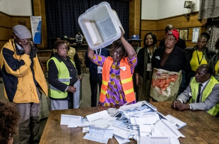 Un agent électoral renverse une urne lors des opérations de dépouillement des bulletins de vote pour les élections générales au Zimbabwe, le 30 juillet 2018 à Harare.