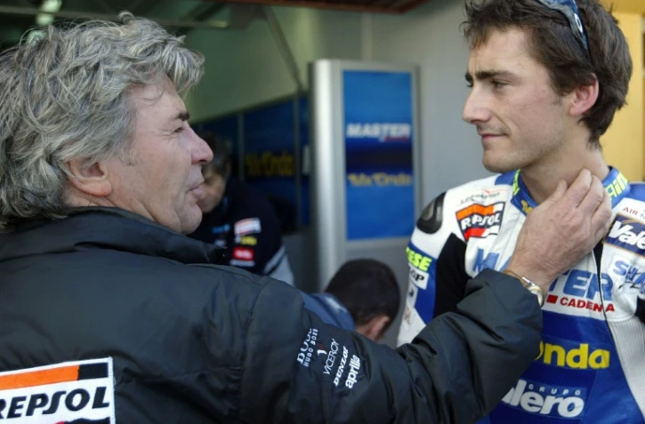 L'ancien champion du monde espagnol de moto Angel Nieto (g) félicite son fils Pablo, 2e sur la grille de départ des 125 cc au GP de la Communauté de Valence, le 1er novembre 2003 à Cheste en Espagne