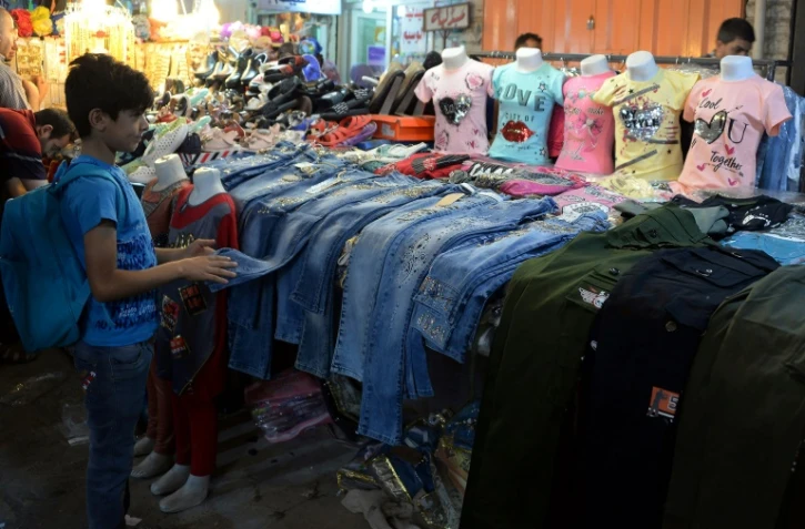 Un garçon irakien regarde des jeans sur un marché le 14 juin 2018. A Mossoul, pour l'Aïd el-Fitr, les petits Irakiens recevront des jouets en pagaille mais pas de pistolets et autres armes en plastique, pour tourner la page des jihadistes du groupe Etat islamique (EI)