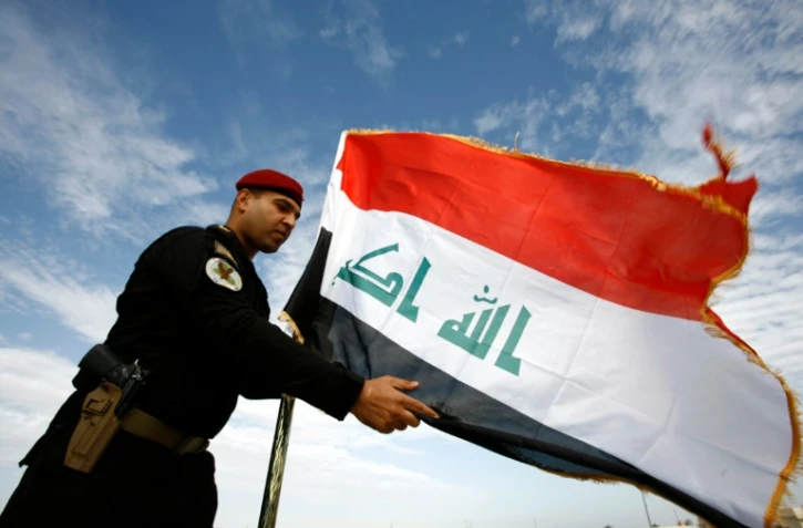 Un policier irakien devant le drapeau de l'Irak, Ă Najaf le 9 janvier 2016