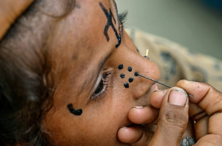 Un tatouage traditionnel est dessiné sur le visage de la jeune Champa, 7 ans, à la colonie Jogi à Umerkot, un district à majorité hindoue, le 14 juillet 2025 au Pakistan