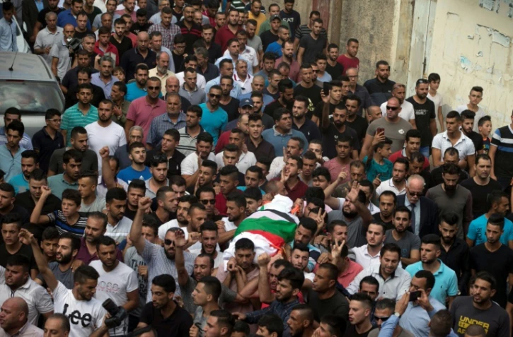 Des hommes transportent le corps d'une mère de famille palestinienne, tuée selon les forces de sécurité palestiniennes par des jets de pierre de colons israéliens, lors de ses funérailles à Bidya, en Cisjordanie occupée, le 13 octobre 2018