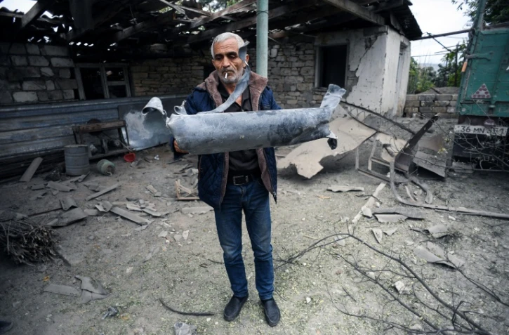 Un homme montre un fragment d'un obus tombé devant la maison de son frère dans la ville de Martuni le 1er octobre 2020.