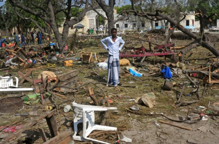 Le 11 décembre 2016 un homme se trouve au milieu d'objets épars sur les lieux de l'attentat-suicide au camion piégé près de l'entrée du port de Mogadiscio et qui a fait plus de 20 morts