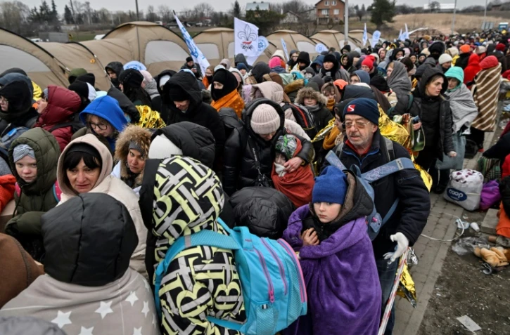 Des réfugiés font la queue dans le froid en attendant d'être transférés dans une gare après avoir traversé la frontière ukrainienne vers la Pologne, au poste frontière de Medyka en Pologne, le 7 mars 2022