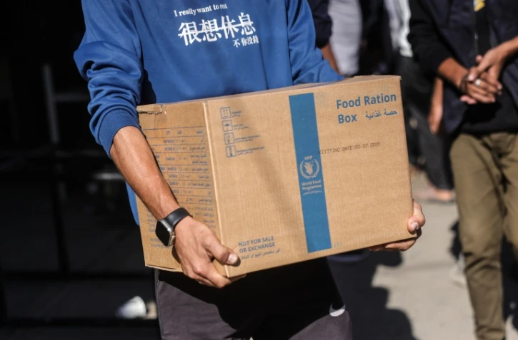 Un Palestinien porte un colis alimentaire fourni par le Programme alimentaire mondial le 27 octobre 2025 dans le centre de la bande de Gaza