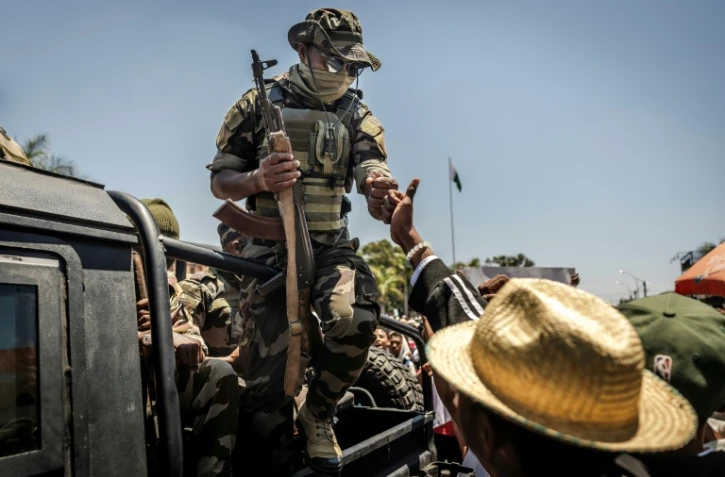 Un militaire malgache salue du poing un civil alors que des manifestants se rassemblent pour un meeting de la société civile devant l'hôtel de ville d'Antananarivo, le 13 octobre 2025