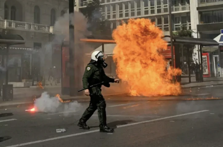 Un policier passe à proximité d'un cocktail molotov lors de heurts en marge d'une manifestation, le 5 mars 2023 à Athènes ( AFP / Louisa GOULIAMAKI )