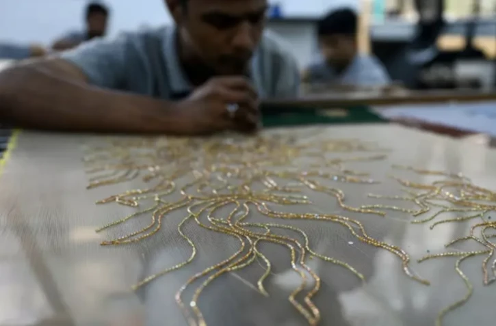 Des brodeurs de l'atelier Shanagar travaillent sur une pièce de tissu pour le couturier français Julien Fournié, le 7 janvier 2023 à Bombay, en Inde ( AFP / Punit PARANJPE )