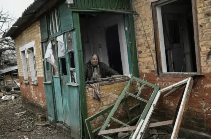 Une femme âgée derrière une fenêtre de sa maison endommagée par un bombardement à Tchassiv Iar, près de Bakhmout, le 11 mars 2023 ( AFP / Aris Messinis )