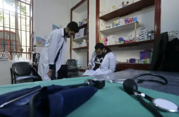 Deux étudiants en médecine regardent un livre d'allemand, dans un dispensaire à Damas le 21 janvier 2023 ( AFP / LOUAI BESHARA )