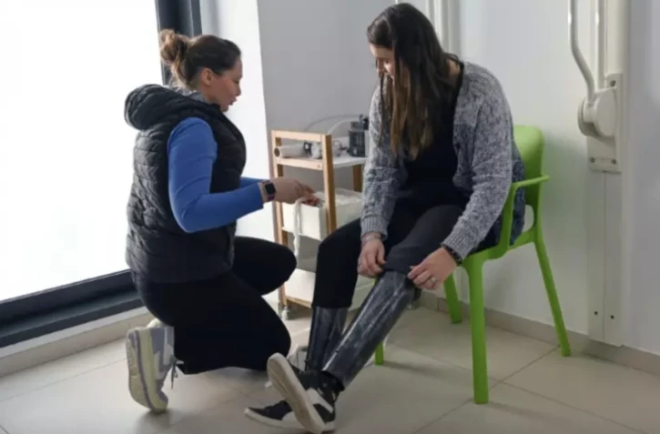 Estelle Lehouck (d), amputée des deux jambes jusqu'aux genoux, essaie sa nouvelle prothèse à paillettes chez son orthoprothésiste Marion Fourmaux à Méteren, dans le Nord, le 30 janvier 2023 ( AFP / DENIS CHARLET )