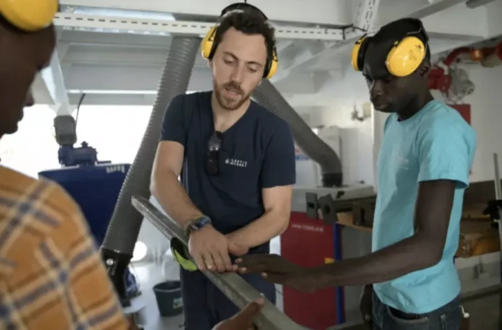 Un casque jaune vissé sur les oreilles, Baptiste Lomenech, explique à une dizaine de jeunes entrepreneurs du Sénégal le fonctionnement de l'extrudeuse, une machine qui sert au recyclage du plastique ( AFP / SEYLLOU )
