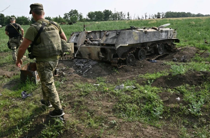 Un soldat ukrainien passe à proximité d'un char russe détruit dans un champ au sud de la ville de Mykolaiv (Ukraine) le 12 juin 2022